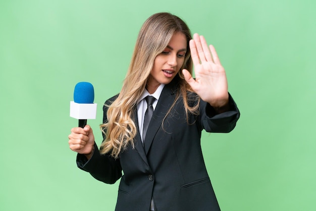 Young pretty Uruguayan tv presenter over isolated background making stop gesture and disappointed