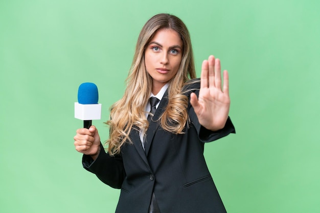 Young pretty Uruguayan tv presenter over isolated background making stop gesture