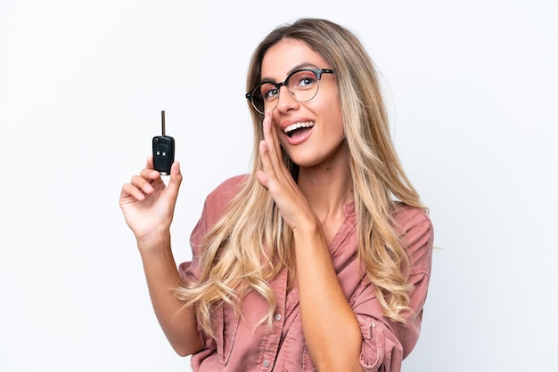 Young pretty Uruguayan woman holding car keys isolated on white background whispering something