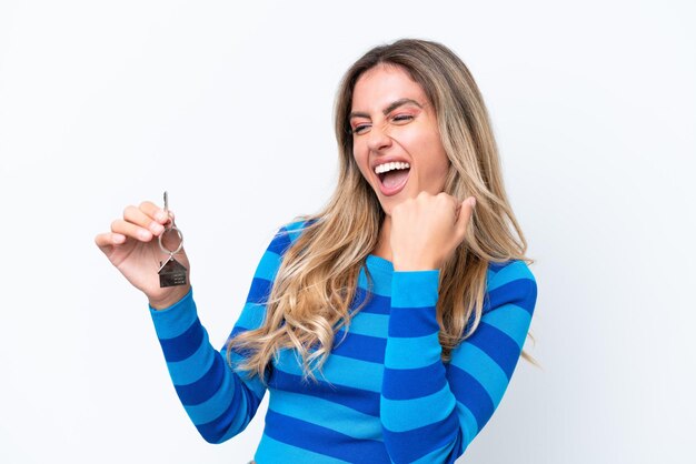 Young pretty Uruguayan woman holding home keys isolated on white background celebrating a victory