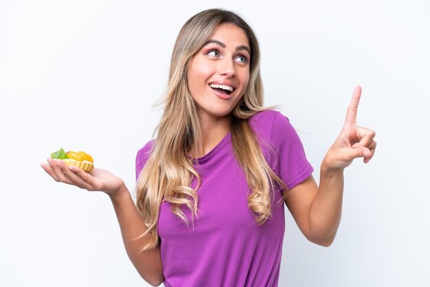 Young pretty Uruguayan woman holding a tartlet isolated on white background intending to realizes the solution while lifting a finger up