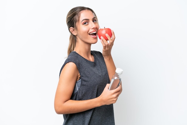 Young pretty Uruguayan woman isolated on white background with an apple and with a bottle of water