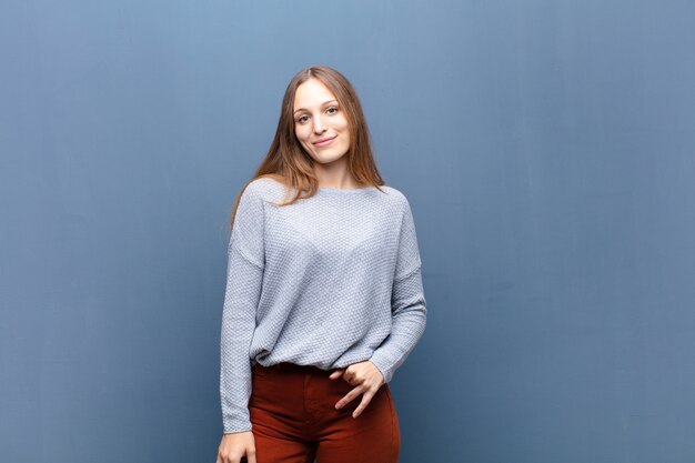 Young pretty woman against blue wall with a copy space