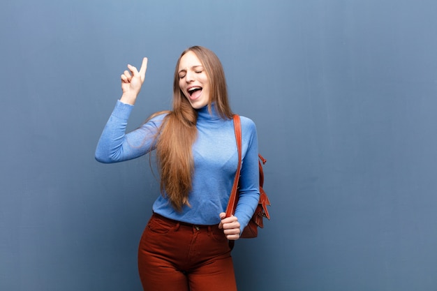 Young pretty woman against blue wall with a copy space