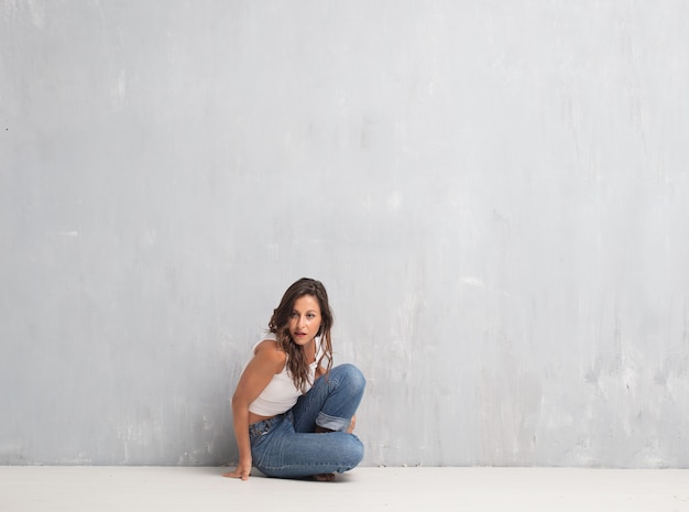 Young pretty woman against cement wall background with a copy sp