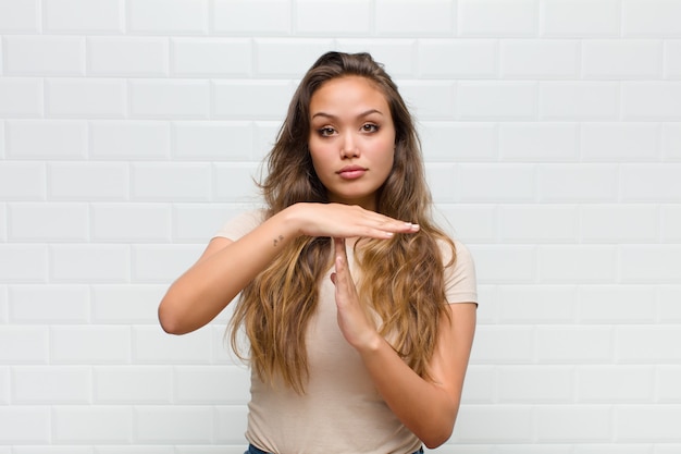 Foto giovane donna graziosa contro il muro bianco