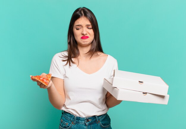 Young pretty woman angry expression and holding a pizza