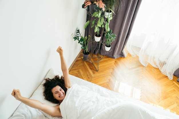 Young pretty woman in bed with white sheets bright light