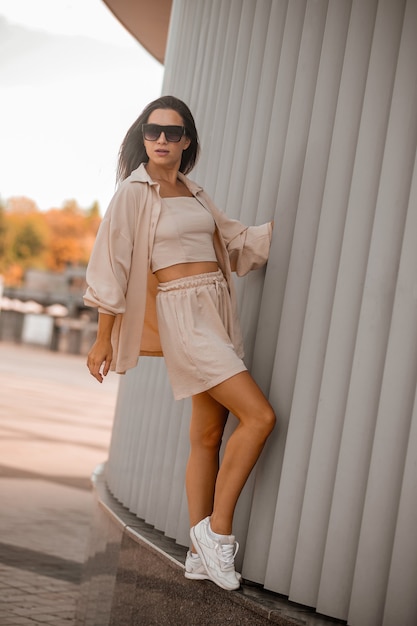 A young pretty woman in beige clothes and in sunglasses