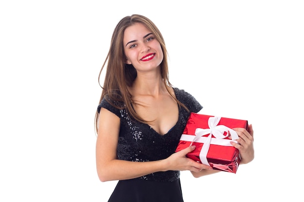 Young pretty woman in black dress holding red present on white background in studio