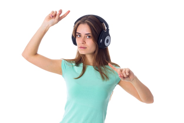 Young pretty woman in blue Tshirt listening to the music in black headphones in studio