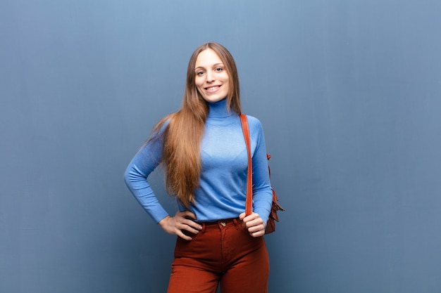 Young pretty woman on blue wall with a copy space