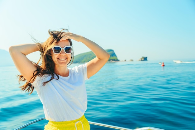 Photo young pretty woman at boat nose sea with mountains and island on background