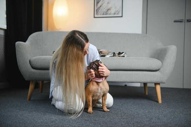 Молодая красивая женщина в повседневной одежде обнимает свою собаку, сидящую на диване в гостиной своего уютного загородного дома Концепция общения с животными