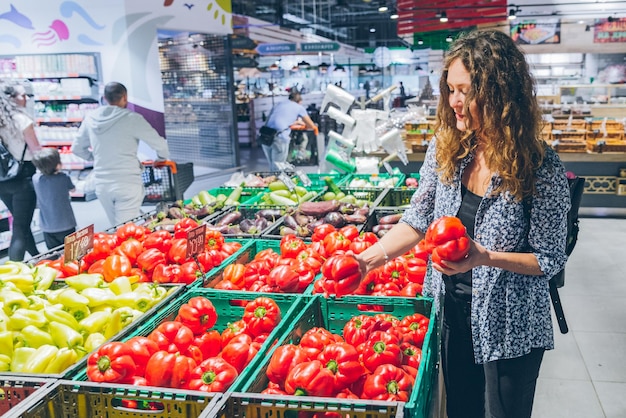 Young pretty woman choosing salad paper in grocery store