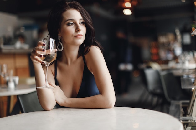 young pretty woman in dress in cafe with glass of wine