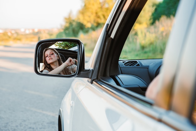 日没時に車を運転する若いきれいな女性。暖かい晴れた日