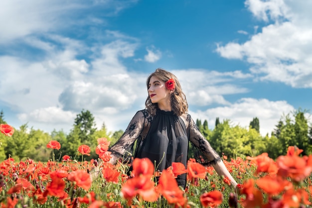 Young pretty woman enjoying summer time in the poppies flower field. freedom