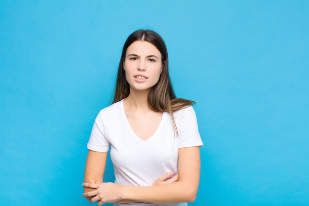 不安、病気、病気、不幸な感じの若いきれいな女性、青い壁に痛みを伴う胃の痛みやインフルエンザに苦しんでいます。