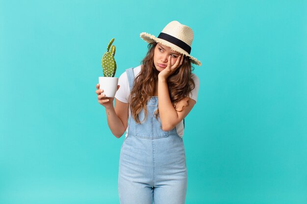 Young pretty woman feeling bored, frustrated and sleepy after a tiresome and holding a cactus