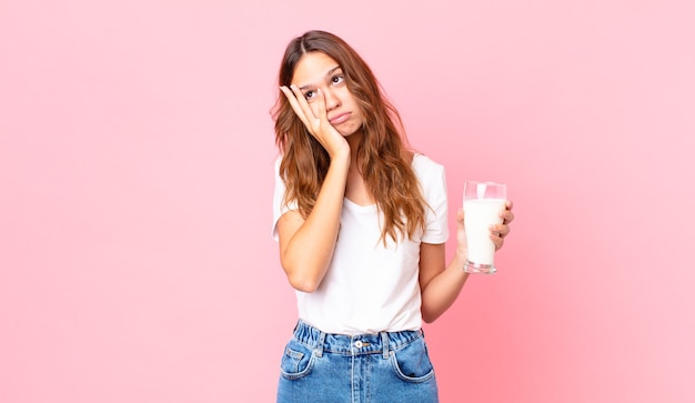 Young pretty woman feeling bored, frustrated and sleepy after a tiresome and holding a glass of milk