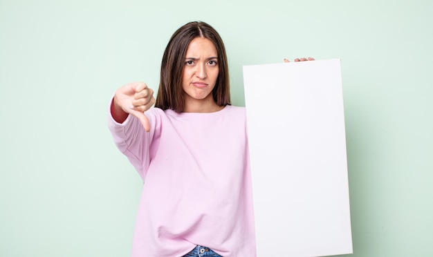 Photo young pretty woman feeling cross,showing thumbs down. empty canvas concept