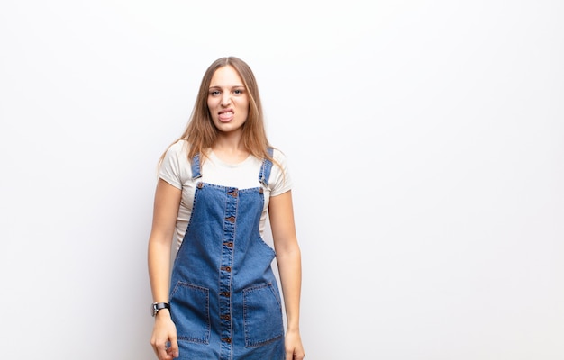 Photo young pretty woman feeling disgusted and irritated, sticking tongue out, disliking something nasty and yucky over white wall