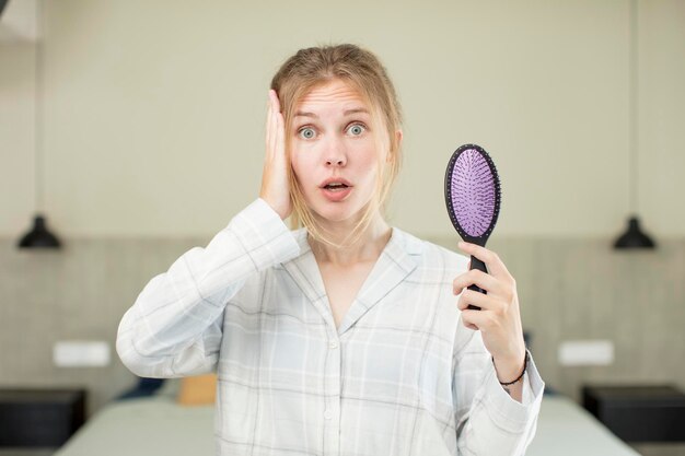 Photo young pretty woman feeling extremely shocked and surprised hair comb concept