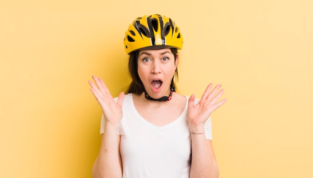 Young pretty woman feeling happy and astonished at something unbelievable bike helmet concept