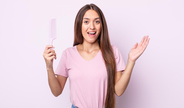 Young pretty woman feeling happy and astonished at something unbelievable. hair comb concept