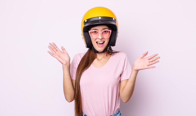 信じられないほどの何かに幸せと驚きを感じている若いきれいな女性。バイクのライダーとヘルメット