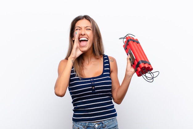 Giovane bella donna che si sente felice, eccitata e positiva, gridando con le mani vicino alla bocca, gridando con una bomba alla dinamite