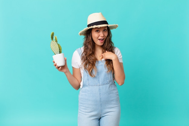 Young pretty woman feeling happy and pointing to self with an excited and holding a cactus