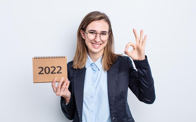 Young pretty woman feeling happy, showing approval with okay gesture. calendar concept