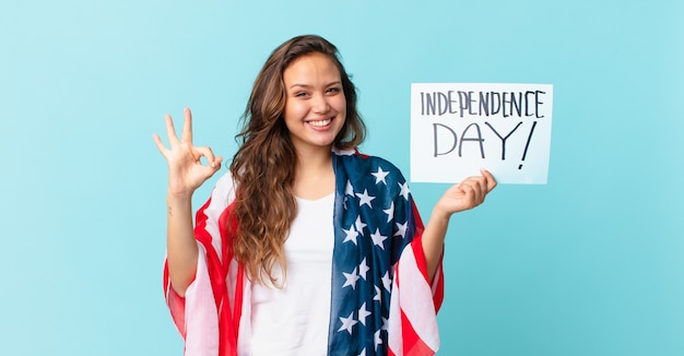 Young pretty woman feeling happy, showing approval with okay gesture independence day concept