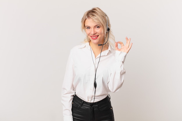 Young pretty woman feeling happy, showing approval with okay gesture. telemarketing concept