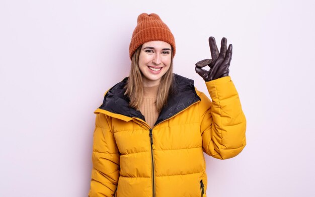 Young pretty woman feeling happy, showing approval with okay gesture. winter concept