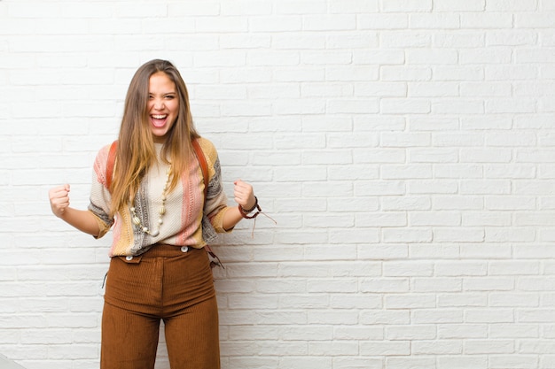 Young pretty woman feeling happy, surprised and proud, shouting and celebrating success with a big smile