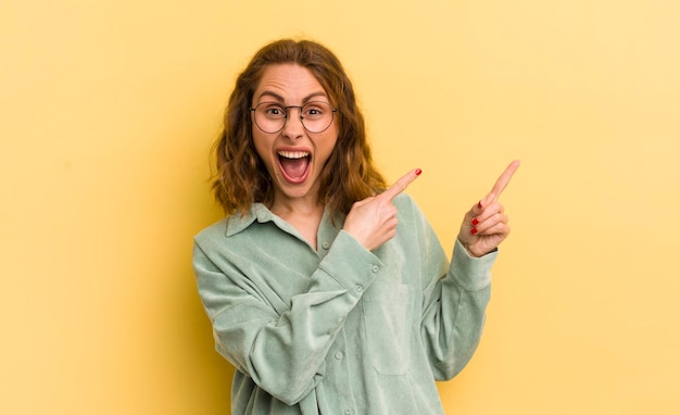 Photo young pretty woman feeling joyful and surprised smiling with a shocked expression and pointing to the side