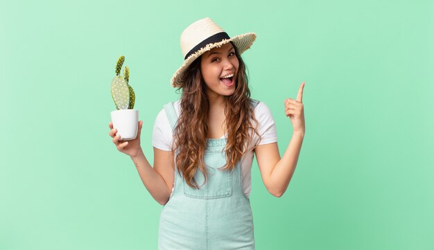 Young pretty woman feeling like a happy and excited genius after realizing an idea and holding a cactus