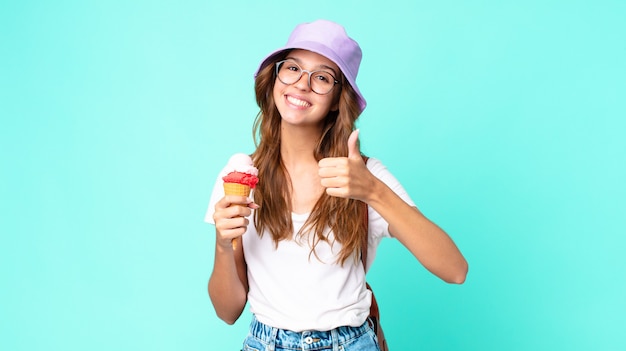 Young pretty woman feeling proud,smiling positively with thumbs up holding an ice cream. summer concept