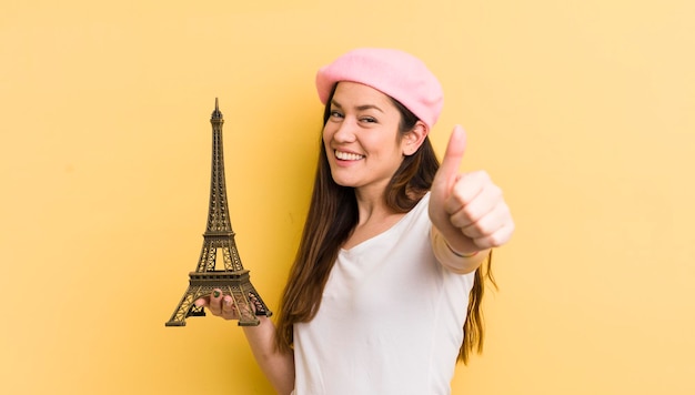 Young pretty woman feeling proudsmiling positively with thumbs up paris concept