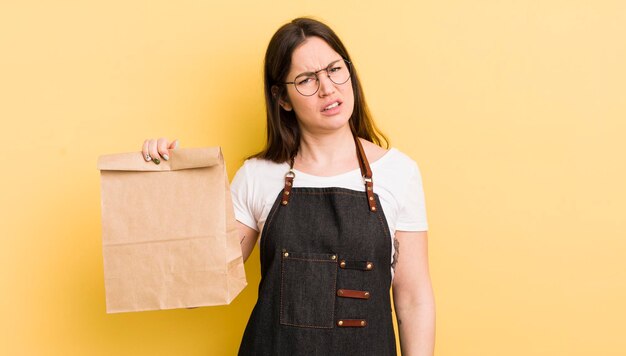 Young pretty woman feeling puzzled and confused fast food courier