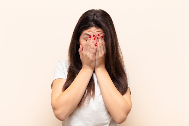 Foto giovane bella donna sentirsi triste, frustrata, nervosa e depressa, coprendosi il viso con entrambe le mani, piangendo