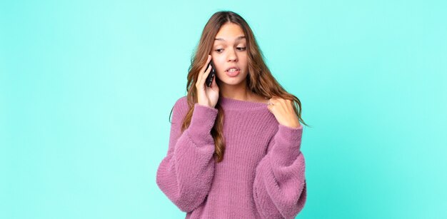 ストレス、不安、倦怠感、欲求不満を感じ、スマートフォンを使用している若いきれいな女性