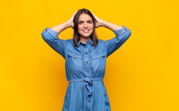 Young pretty woman feeling stressed, worried, anxious or scared, with hands on head, panicking at mistake