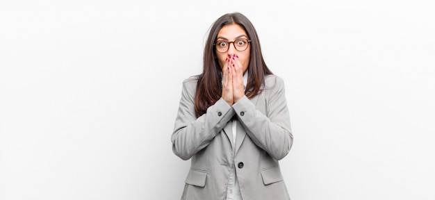 Young pretty woman feeling worried, upset and scared, covering mouth with hands, looking anxious and having messed up isolated against white wall