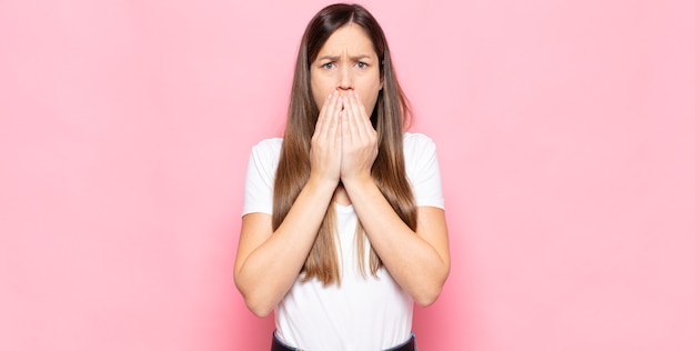 Young pretty woman feeling worried, upset and scared, covering mouth with hands, looking anxious and having messed up