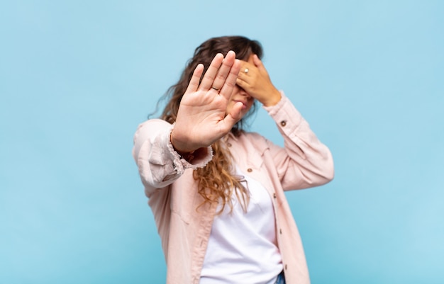 young pretty woman gesturing on blue wall