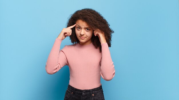 Young pretty woman gesturing on colored wall